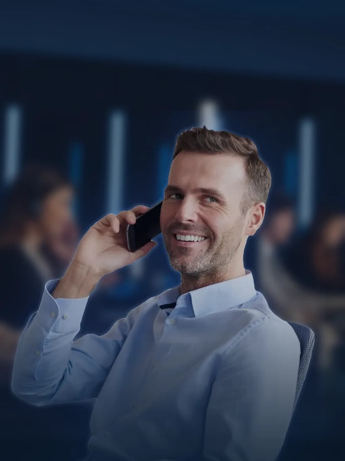 Un chargé de prospection souriant, au téléphone avec un prospect, dans un plateau d'appels le soir.