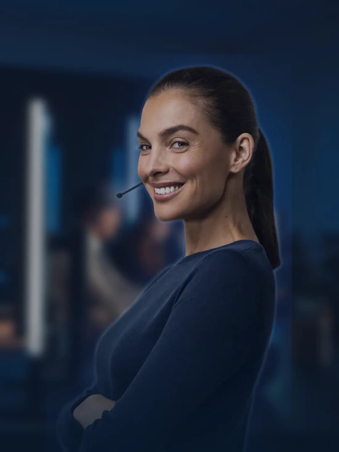 Une téléprospectrice souriante, casque-micro sur la tête, dans un plateau d'appels le soir.