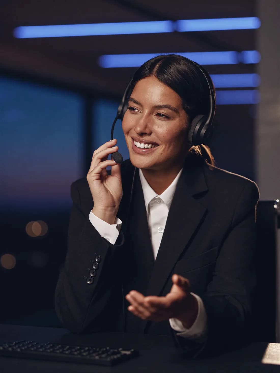 Une téléprospectrice en casque-micro, en pleine conversation téléphonique sur un plateau le soir